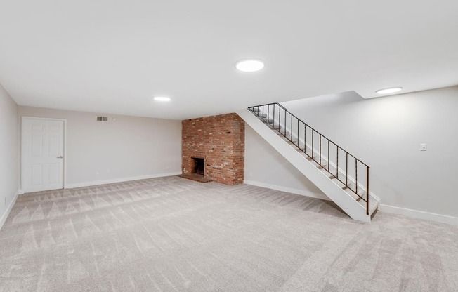 A room with a carpeted floor and a staircase leading to a loft.