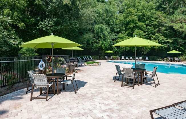 a patio with tables and umbrellas next to a swimming pool