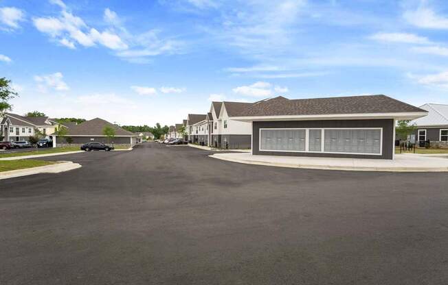 A large, modern building with a grey roof and a parking lot in front.