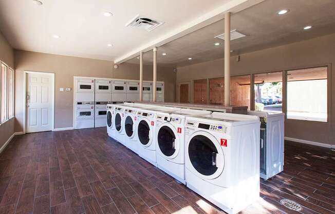 A laundry room with a row of washers and dryers.