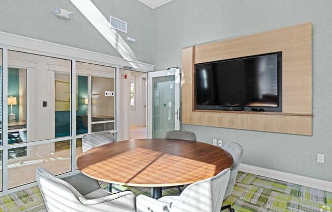 A conference room with a table, chairs, and a television.