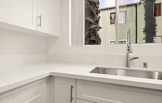 A kitchen with white cabinets and a silver sink.