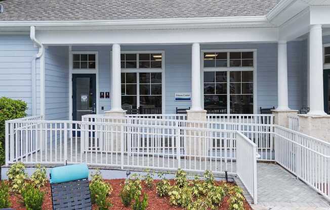 A blue house with a white porch and a sign that says "Welcome".