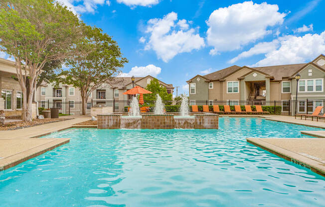 San Antonio, TX Apartments - Club at Stone Oak - Resort-Style Pool with Water Feature, Lounge Chairs, Umbrellas, and Beautiful Landscaping