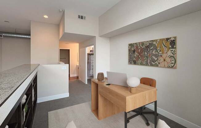 A room with a desk and a chair with a painting on the wall.