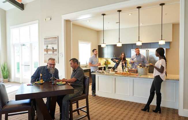 a group of people sitting around a table in a kitchen at The Winhall of Williams Pointe Apartments, Waukee, 50263