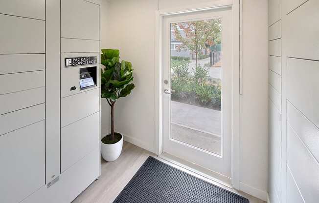 Secure package concierge system indoors by exterior door. Area contains a plant and rug. at 3030 Lake City, Seattle