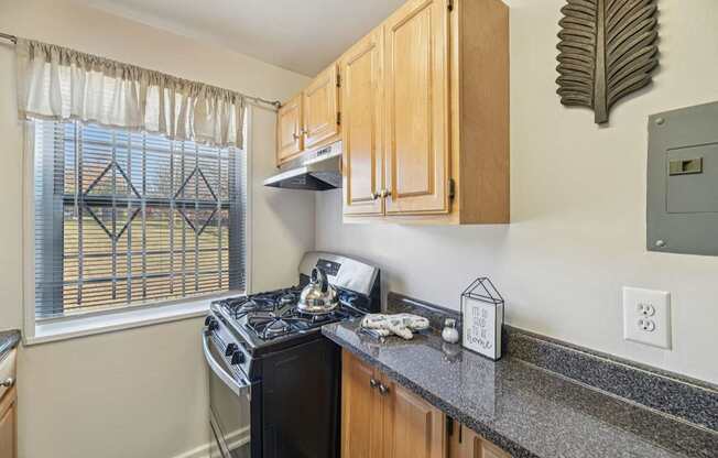 A kitchen with a black stove top oven and wooden cabinets.