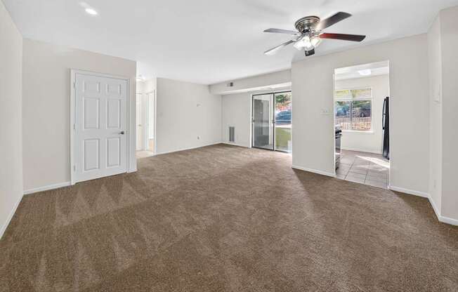 A spacious room with a carpeted floor and a ceiling fan.
