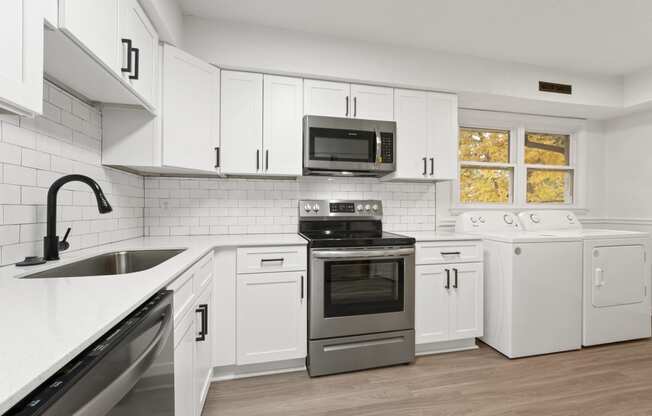 a kitchen with white cabinets and stainless steel appliances