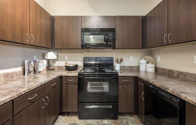 A kitchen with a black stove top oven and wooden cabinets.