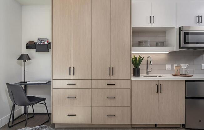 a kitchen with white cabinets and a white countertop with a sink and a microwave