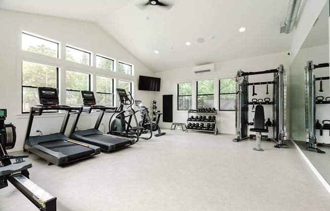 A spacious gym with treadmills, exercise bikes, and weightlifting equipment.