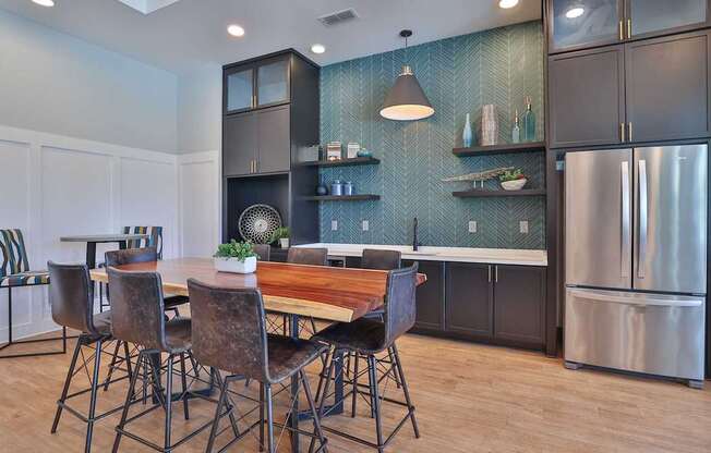 A kitchen with a table and chairs in the foreground and a refrigerator in the background.