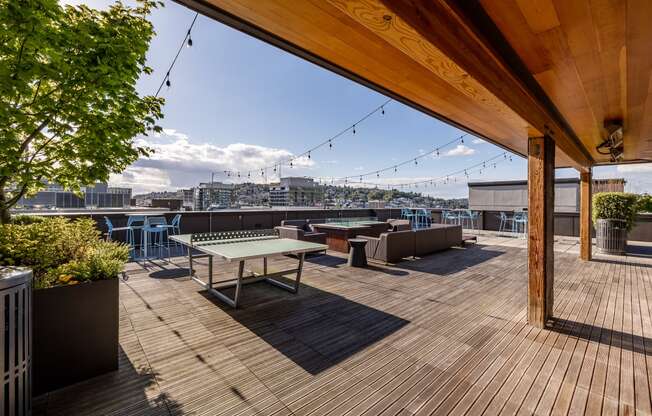 a roof deck with a ping pong table and a view of the city
