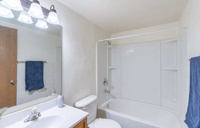 a bathroom with a white tub and a sink and a toilet. Fargo, ND Spring Apartments