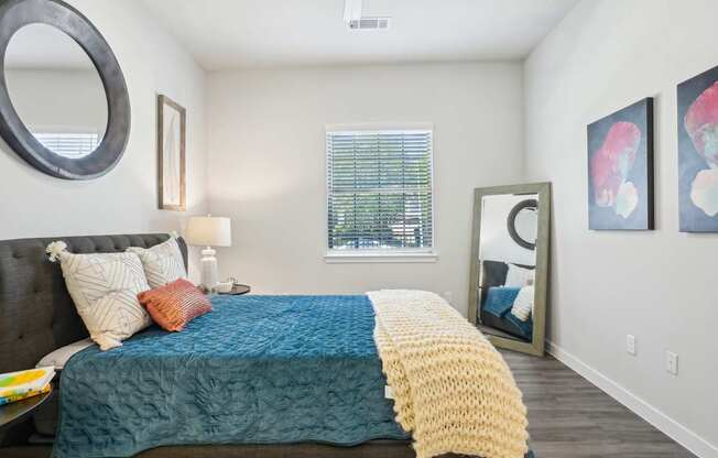 A bedroom with a bed covered in a blue and yellow blanket.