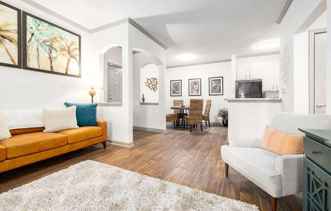 A living room with a yellow sofa and a white rug at The Palms at Chatham apartments in Savannah GA.