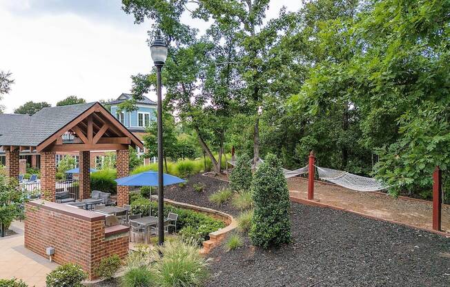a backyard with a hammock and a pavilion and trees