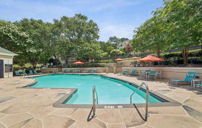 A pool surrounded by trees and chairs at Beacon Ridge Apartments, PRG Real Estate Management, Greenville, 29615