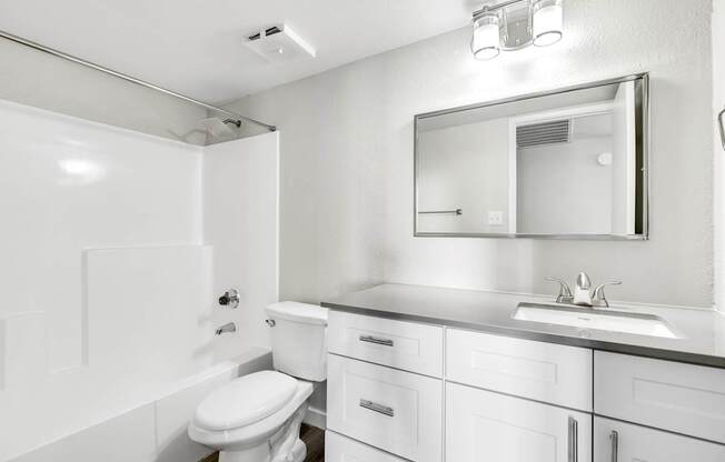 A white bathroom with a toilet, sink, and mirror.