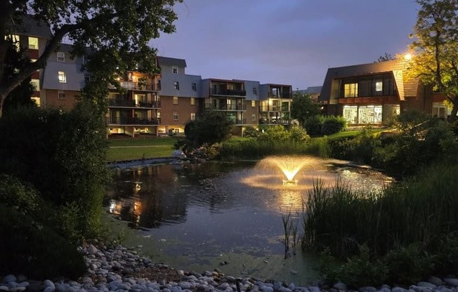 A serene evening view of a pond with a building in the background.