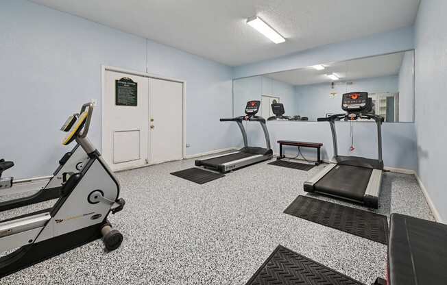 A gym with treadmills and a mirror.