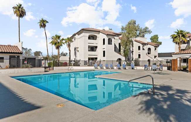 A swimming pool in front of a building with palm trees.
