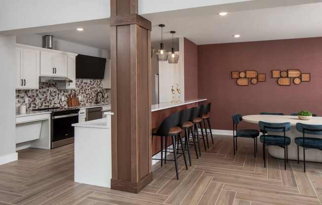 A kitchen with a white island and a dining table with chairs.