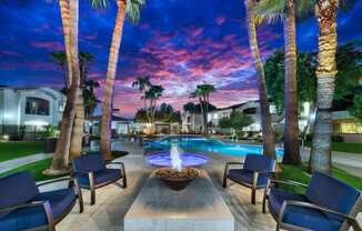 A pool surrounded by palm trees and lounge chairs.