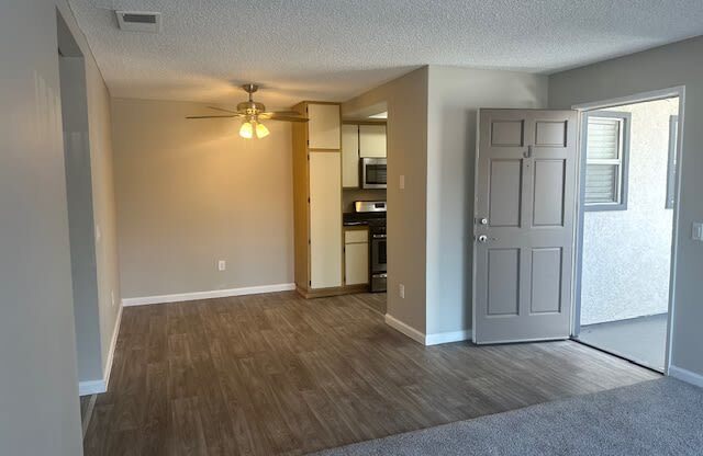 an empty living room and kitchen with a ceiling fanat Lincoln Park Apartments, California