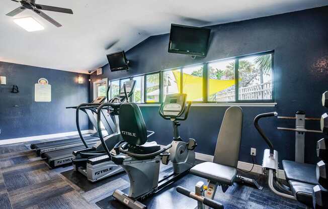 A gym with a variety of equipment including treadmills, exercise bikes, and a television.