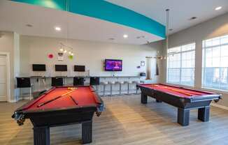 a games room with two pool tables and a tv