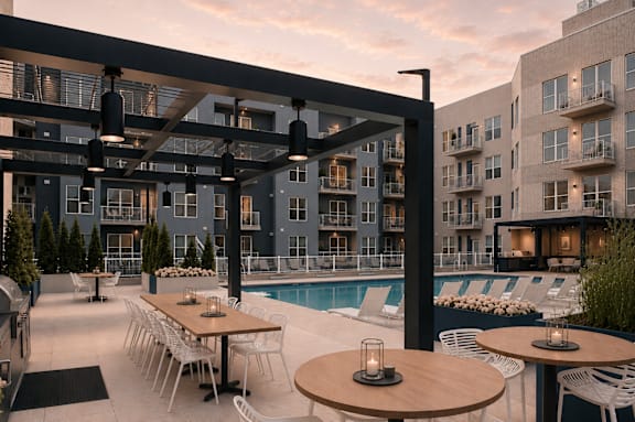 A modern outdoor dining area with tables and chairs is set up next to a pool.