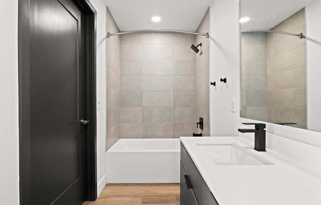 A modern bathroom with a black door and a white bathtub.