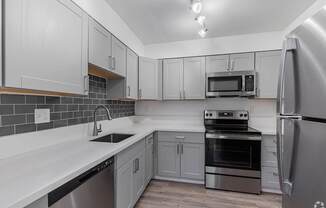 A kitchen with a stainless steel refrigerator, oven, and microwave.