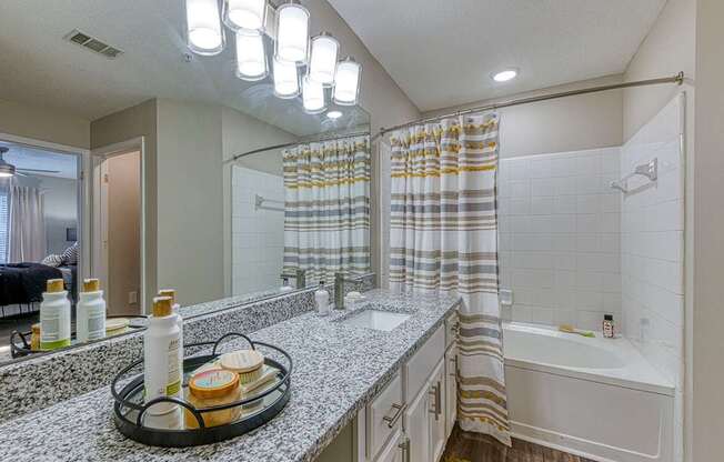 A bathroom with a white tub, sink, and shower curtain.