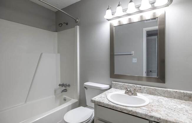 A bathroom with a toilet, sink, and mirror.