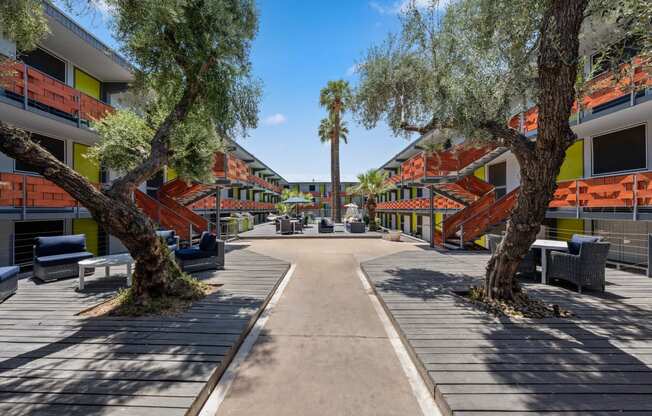 a courtyard with trees and benches and buildings in the background