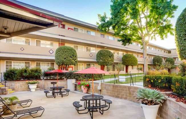A courtyard with tables and chairs is surrounded by a building.