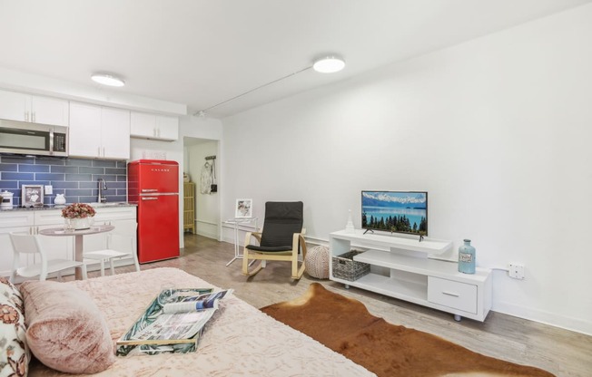 a living room with a couch and a kitchen with a red refrigerator