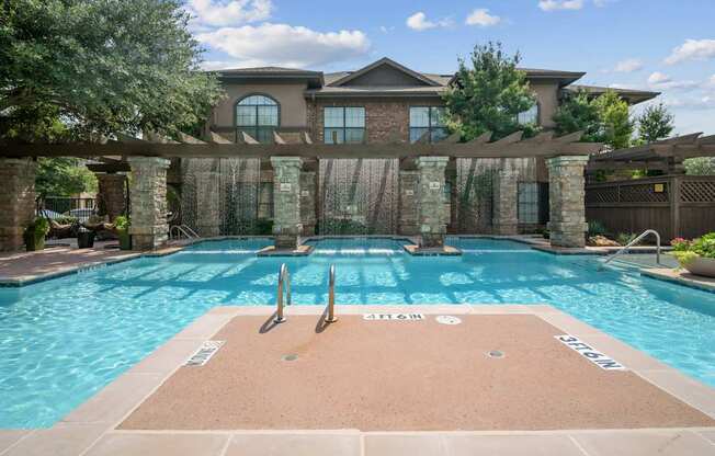 A large swimming pool with a diving board in front of a house.