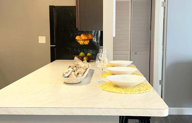 A kitchen counter with a bowl of fruit and a plate of food on it.