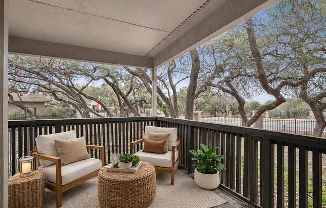 A patio with a chair, a table and a potted plant.