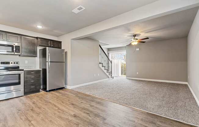 an empty kitchen with stainless steel appliances and a ceiling fan