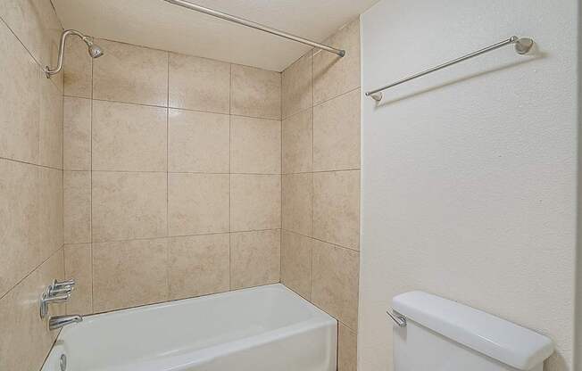 A white bathtub with a shower head and a towel bar.