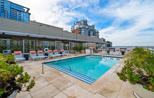 a swimming pool with chairs and a building in the background