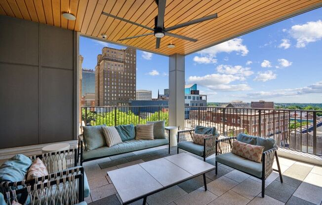 a balcony with a view of the city and a couch and a table at Link Apartments® 4th Street, North Carolina, 27101