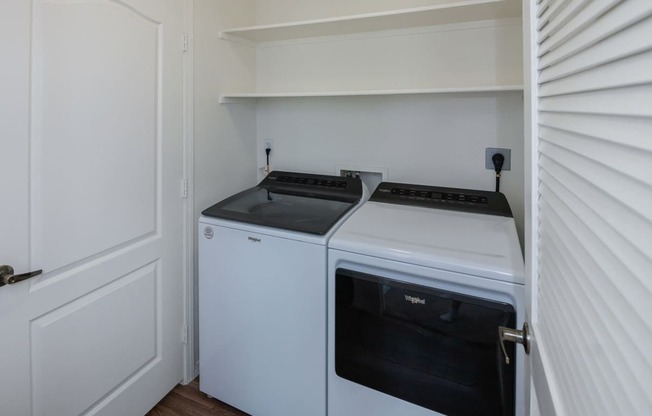 a white washer and dryer in a small room with a white door