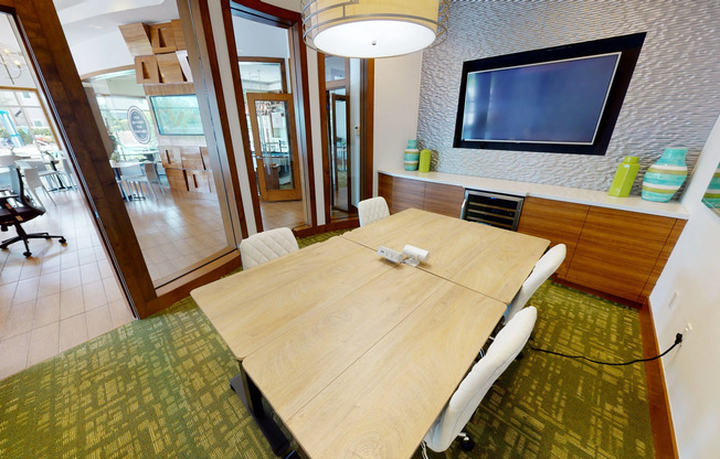 View of Private Conference Room at Apts CoWork Showing Conference Tables, Flat Screen TV, and Glass Doors